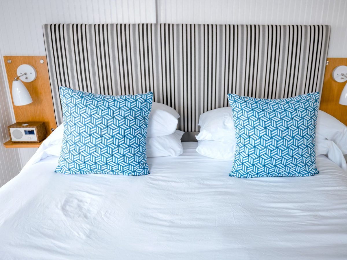 A made-up guest bed with crisp white linen and blue cushions