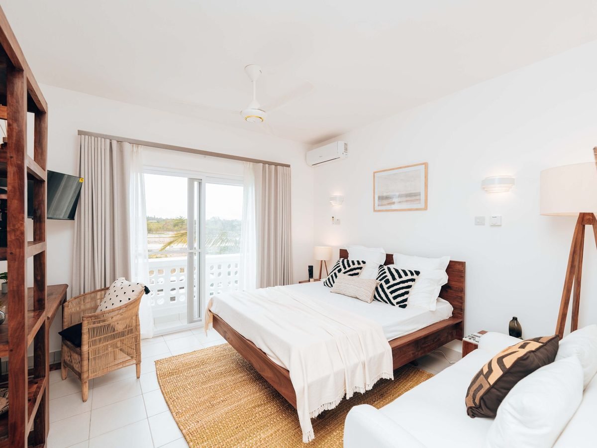 A bright holiday bedroom with timber furniture and white linen
