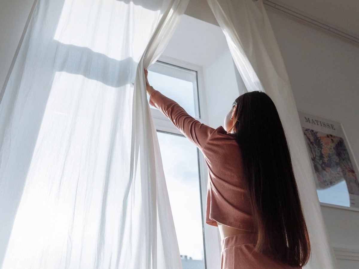White curtains being opened in a bright room