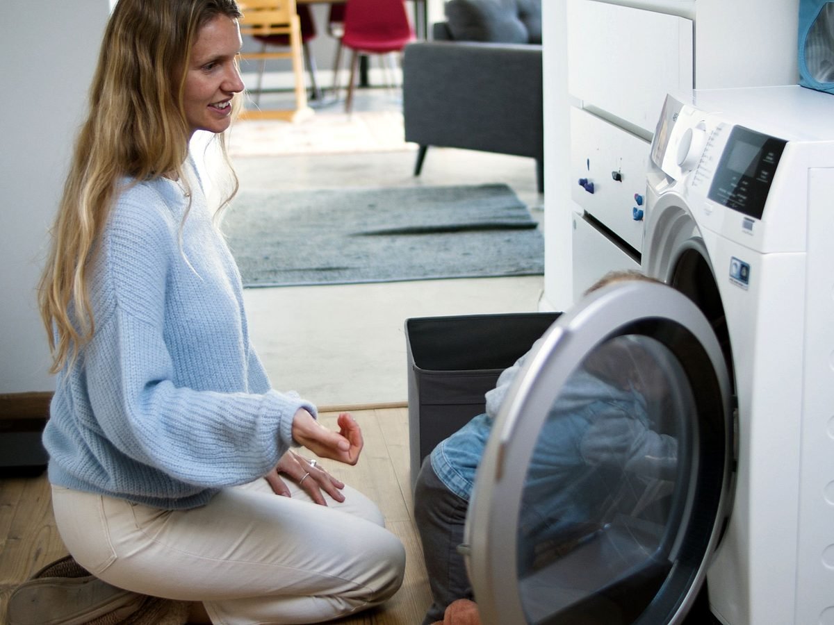 A parent and child loading the washing machine at home